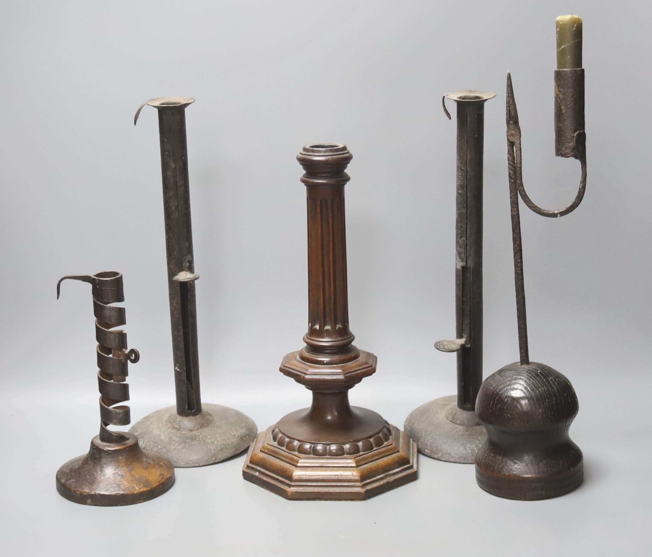 A wrought iron taperstick, a pair of iron telescopic candlesticks, a spiral candlestick, all Georgian and a 17th century style carved wood candlestick (5)